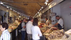 An indoor market with people browsing and selecting seafood. - DiscoverHome Sacramento (Cádiz)