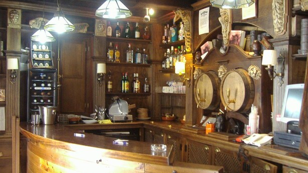 A bar with wooden shelves stocked with bottles, a jukebox, and a vintage telephone. - DiscoverHome Sacramento (Cádiz)