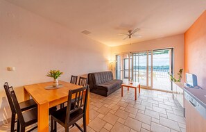 A dining area with a table, chairs, a sofa, and a view of a balcony with a glass door. - 2 bedroom nice apartment in Karbuni (Karbuni)