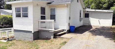 Une petite maison de plain-pied avec un porche à l’avant et un garage.