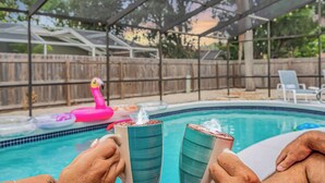 Ett område vid poolen med en överbyggd sittplats, ett trästaket och uppblåsbara poolleksaker.