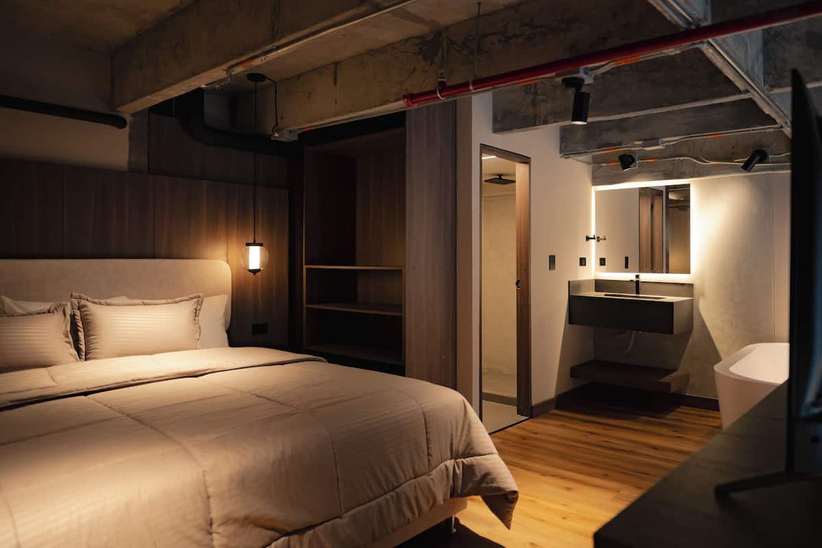Ein modernes Schlafzimmer mit einem großen Bett, einem begehbaren Kleiderschrank und einem Badezimmer mit Spiegel und Waschbecken.
