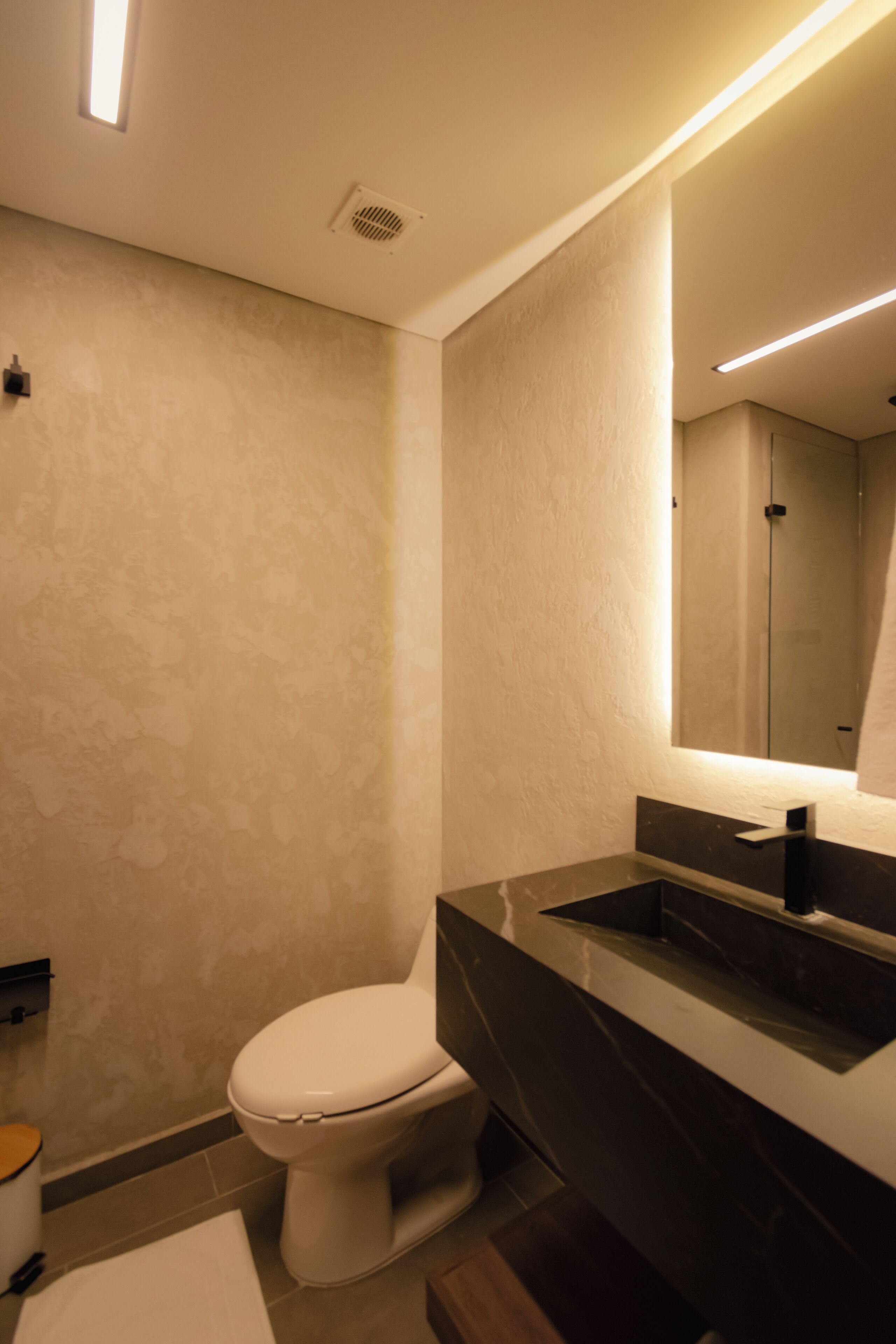 A modern bathroom with a toilet, sink, and mirror.