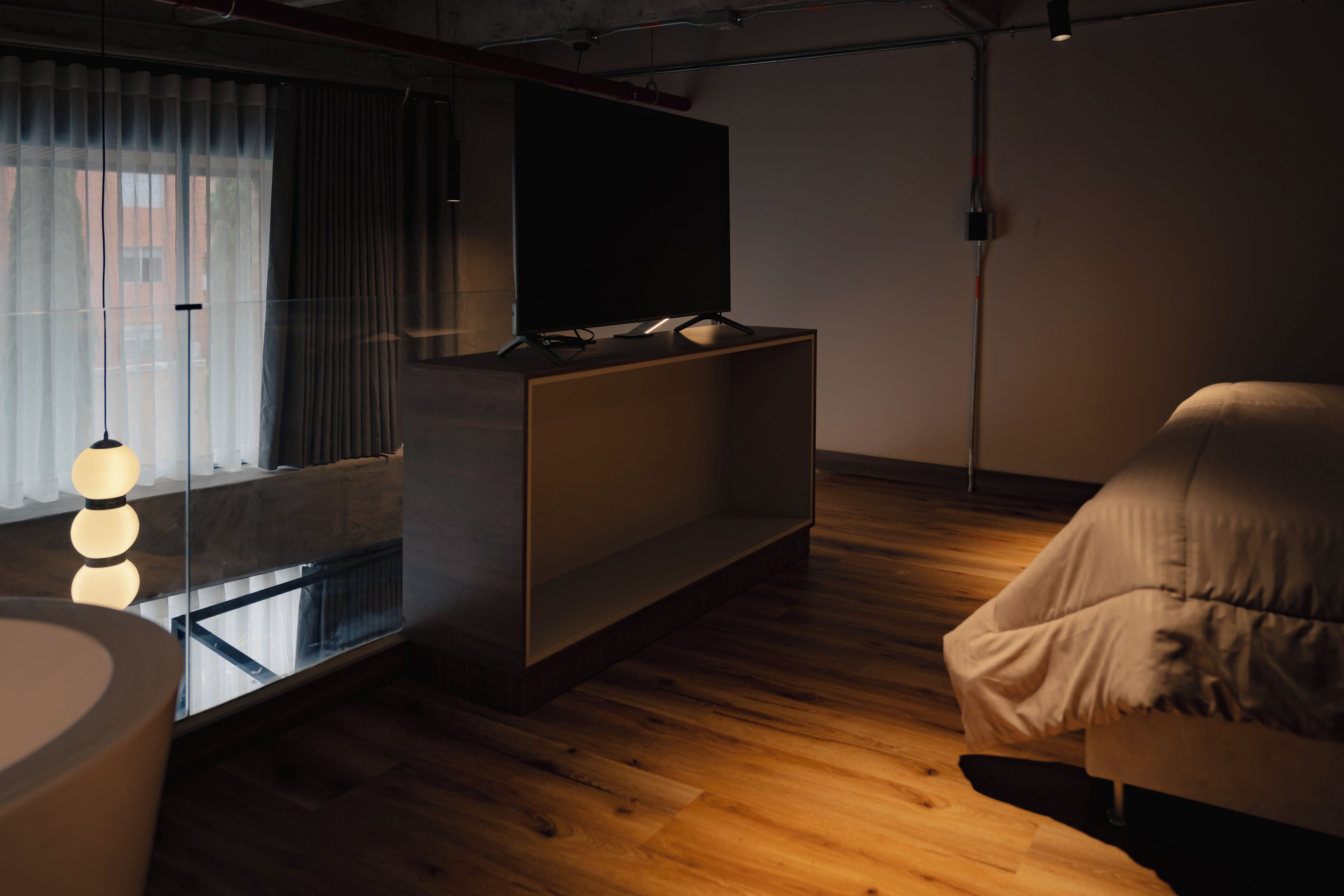 A modern living room with a flat-screen TV on a wooden stand, a glass coffee table, and a sofa.