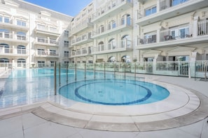 Ein großes Hallenbad, umgeben von einem mehrstöckigen Hotel mit Balkonen und Bogenfenstern.
