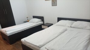 Una habitación con dos camas individuales, un armario y una mesita de noche con lámpara.