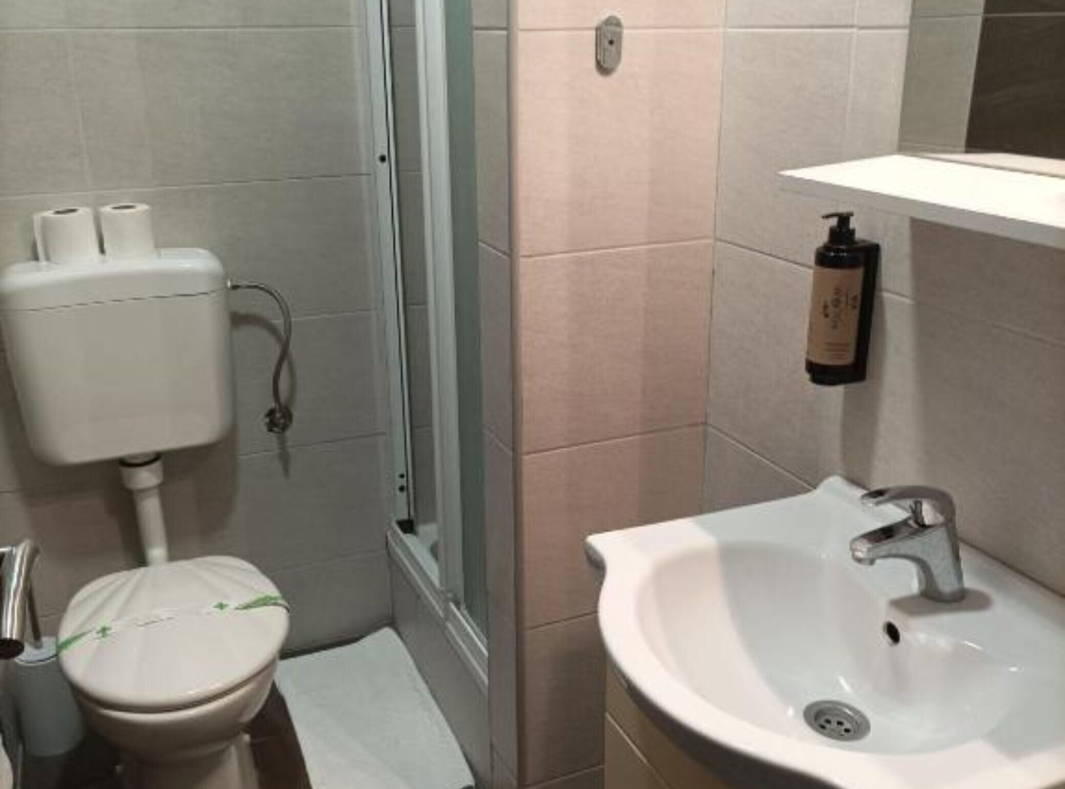 Un baño con inodoro, lavamanos y zona de ducha.