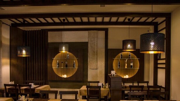 Ein Restaurant mit runden Tischen, dunklen Holzvertäfelungen und hängenden Lampen.