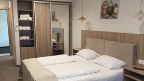 Ein Hotelzimmer mit Doppelbett, einer Garderobe zum Aufhängen, einem Nachttisch und einem Bild an der Wand.