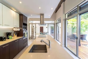 A modern kitchen with a central island, stainless steel appliances, and a view to an outdoor deck. - Casa Harmonia Modern Tropical Villa with Private Pool in Potrero (Potrero)