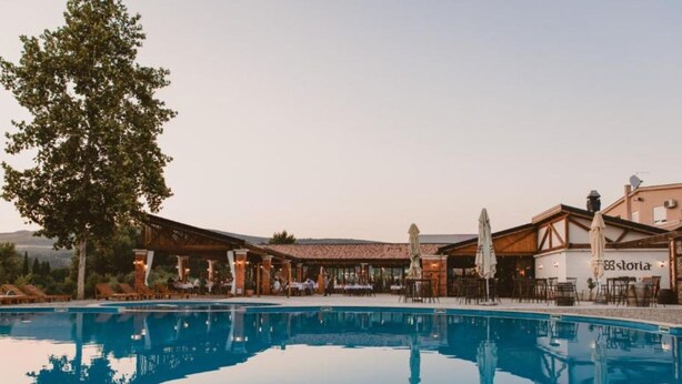 Zona de piscina con un restaurante llamado "storia" y mesas al aire libre.