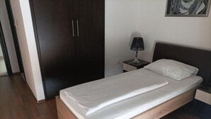 Un dormitorio con cama, mesita de noche, lámpara y armario.