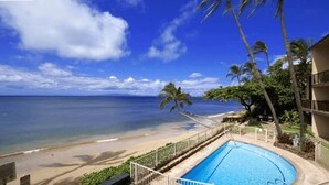 Un hôtel situé en bord de mer, doté d’une piscine, de palmiers et offrant une vue sur l’océan.