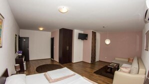 Ett hotellrum med två sängar, en soffa, en TV och ett trägolv.