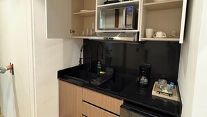 Cocina compacta equipada con microondas, cafetera y refrigerador.