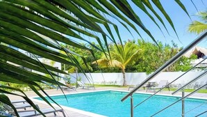 Una piscina con vistas despejadas a la vegetación circundante y una pared blanca al fondo.