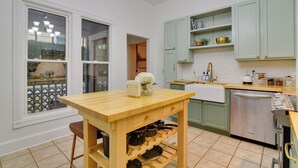 Une cuisine avec une table en bois, un meuble à vin et des armoires vertes.