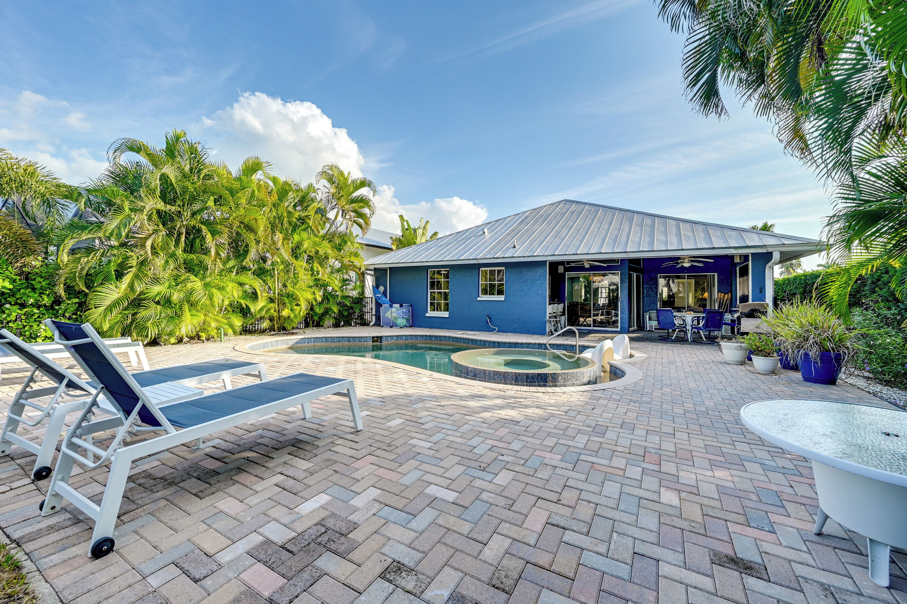 A pool area with lounge chairs, a pool, and a building with a blue exterior.