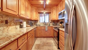 A kitchen with wooden cabinets, granite countertops, stainless steel appliances, and a tiled floor. - Bear's Den 2 Mi to Pinetop CC: Ski, Sled, Hike! (Pinetop Country Club)