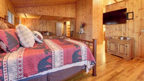 A wooden-paneled bedroom with a large bed, a wooden dresser, a television, and a ceiling fan. - Bear's Den 2 Mi to Pinetop CC: Ski, Sled, Hike! (Pinetop Country Club)