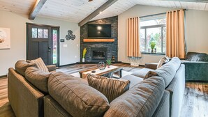 Ein modernes Wohnzimmer mit einem Ecksofa, einem Kamin und einem großen Fernseher.