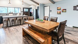 Eine geräumige Küche mit einem großen Holztisch und Barhocker, einem Kühlschrank und einer Spüle.