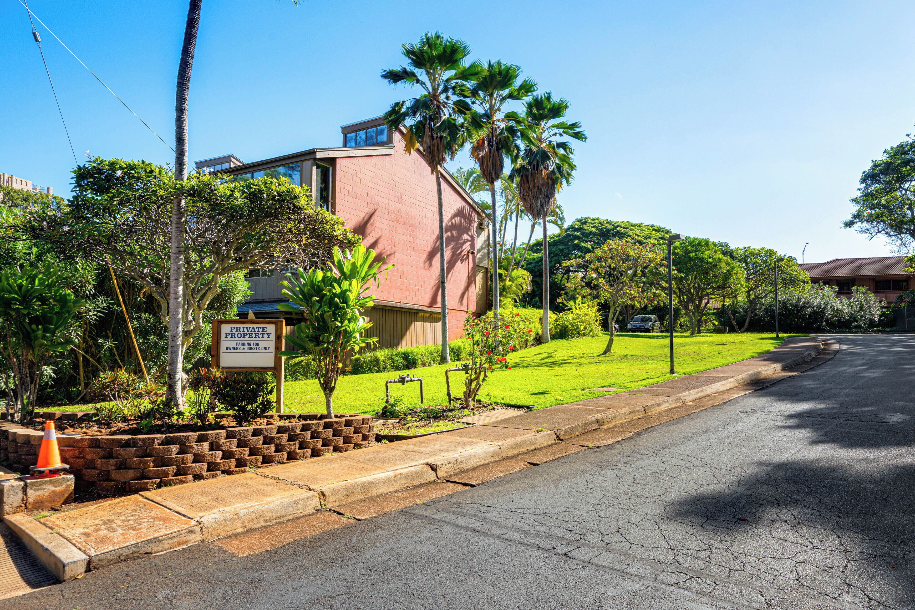Uma propriedade privada com um edifício de tijolos, palmeiras e um gramado bem cuidado.