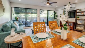 A dining area with a wooden table set for four, surrounded by green upholstered chairs. - Walk to Beach, Pool Access! 'Kahana Coastal Condo' (Lahaina)