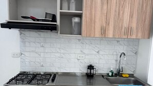 Een moderne keuken met een gasfornuis, een roestvrijstalen spoelbak en houten keukenkastjes.