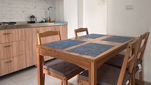 Een moderne keuken met houten kastjes, een ingebouwde kookplaat en een eettafel met stoelen.