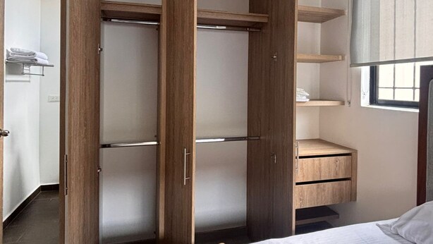 Een slaapkamer met een bed, een open kledingkast en een raam.