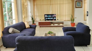 Una sala de estar con dos sofás azul marino, un televisor de pantalla plana y una mesa de centro con plantas.