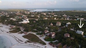 An aerial view of a coastal resort with beachfront properties, a pier, and a beach. - Colorful room very close to the beach. Only one lot behind the best beach | 2 (Holbox Island)