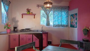 A kitchen with a pink cabinet, a wooden table, and a hanging light fixture. - Colorful room very close to the beach. Only one lot behind the best beach | 2 (Holbox Island)