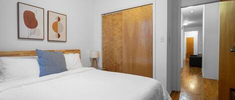 Un dormitorio con una cama, un armario de madera y dos cuadros enmarcados en la pared.