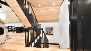 Un interior moderno con una escalera de madera, una puerta negra y un cartel en la pared.
