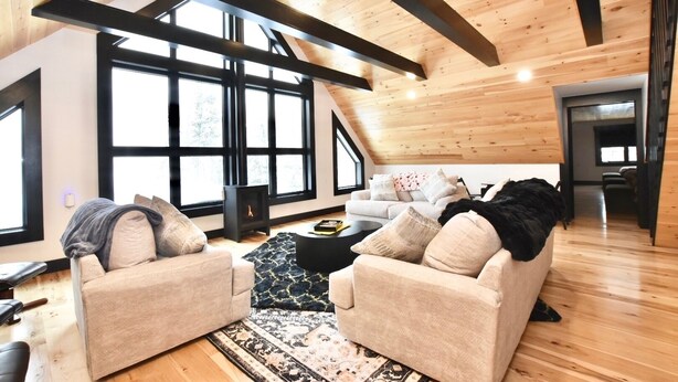 Amplio salón tipo loft con techos altos, ventanas grandes y una chimenea acogedora.