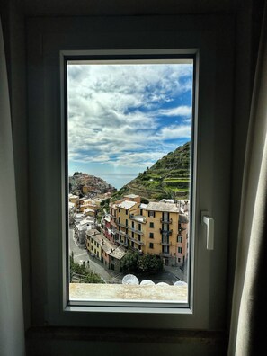 A window with a view of a hillside town, buildings, and a clear sky. - The Manarola Sea View (Manarola)
