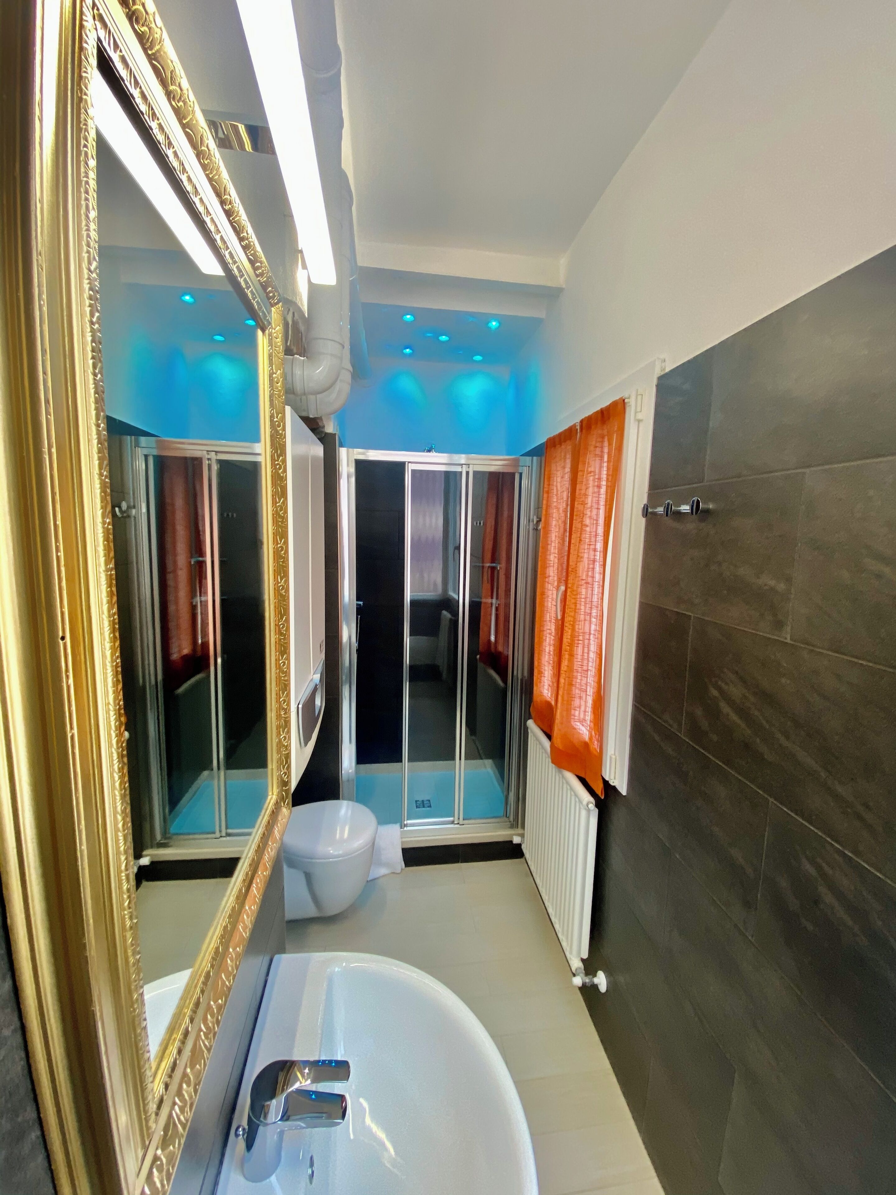 Une salle de bain moderne avec un grand miroir, une baignoire, des toilettes et un espace douche.