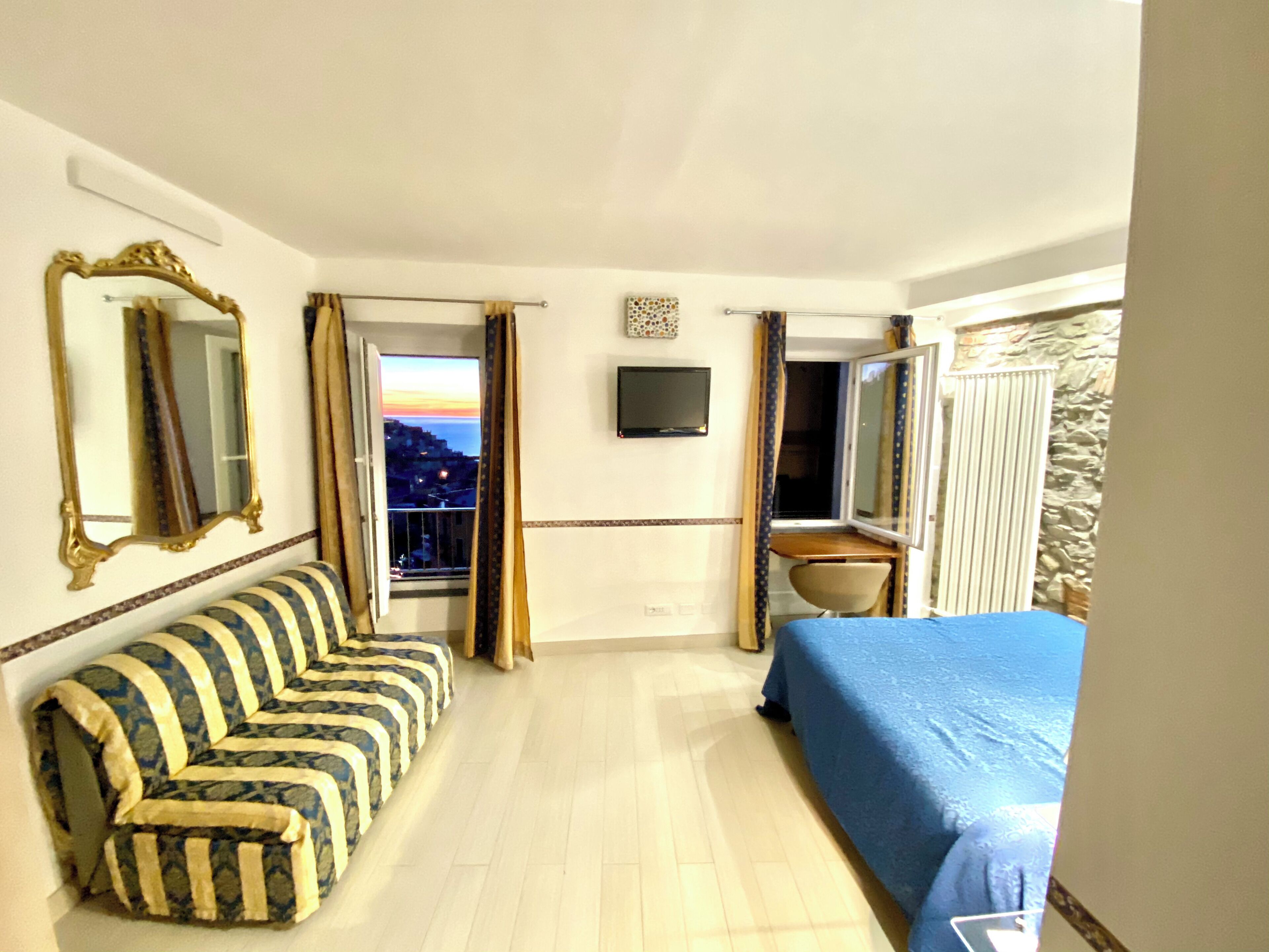 Camera d'albergo con divano, letto, televisione e vista sul mare.