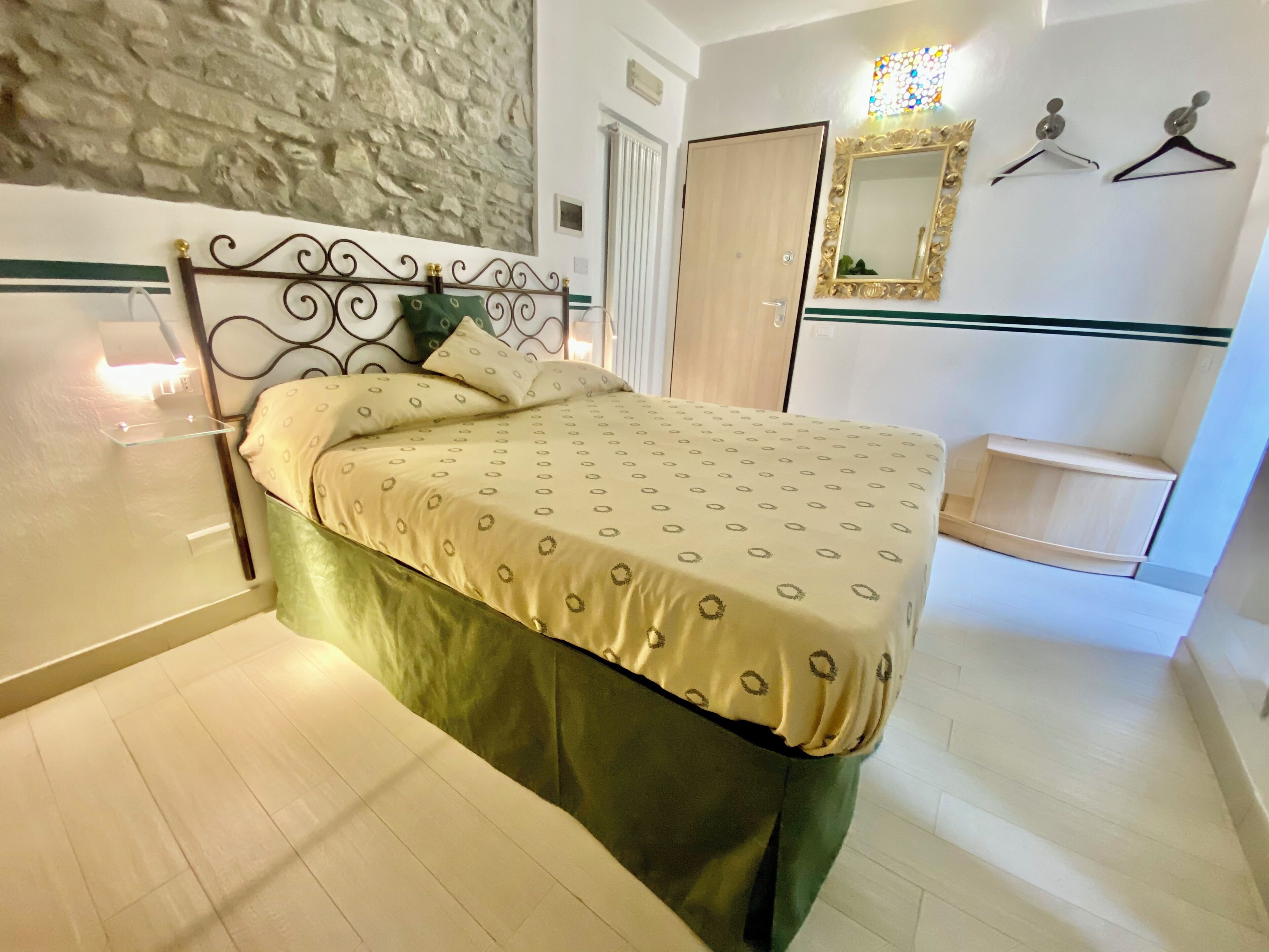 A neatly arranged bedroom with a bed, a bedside table, a mirror, and a wardrobe.