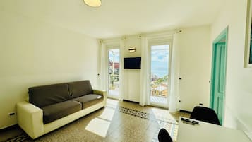 Attico panoramico, letti multipli, balcone, vista oceano | Area soggiorno | TV LED 32 pollici con canali via cavo