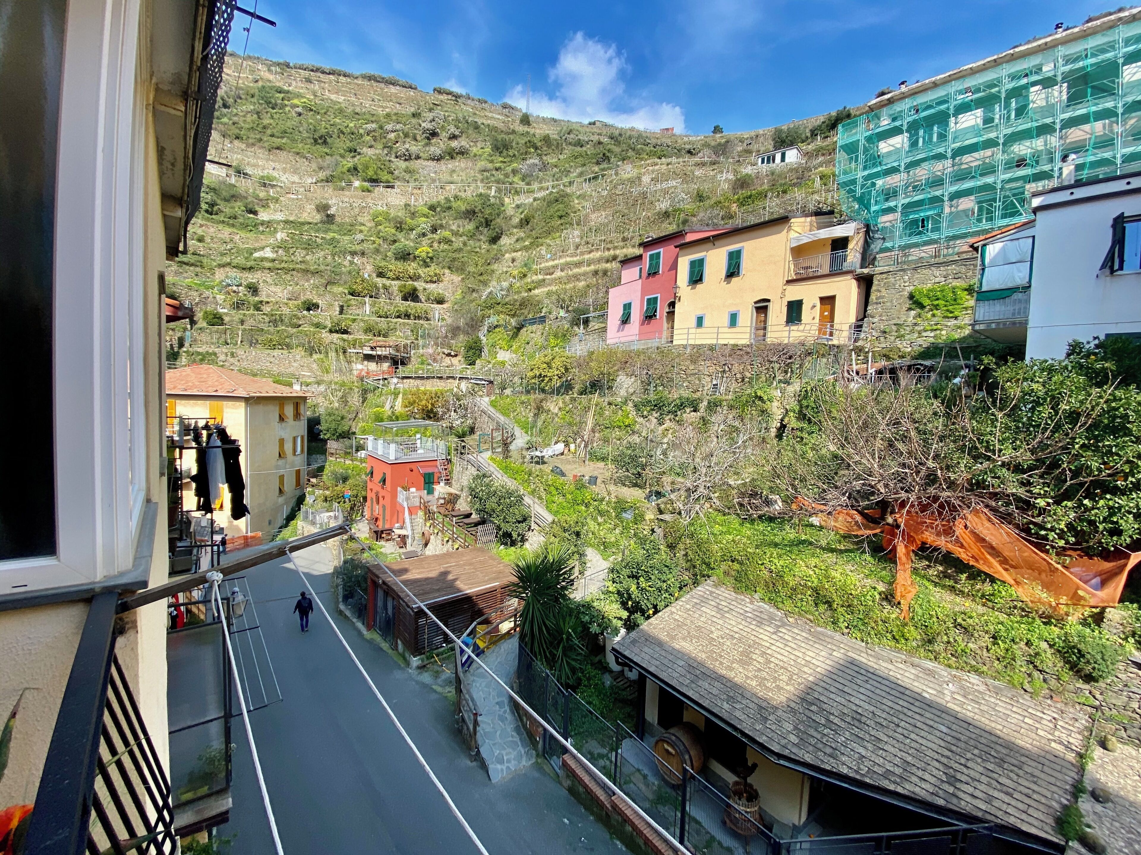 Un village perché sur une colline, avec des maisons à étages, une rue étroite et une personne qui marche.