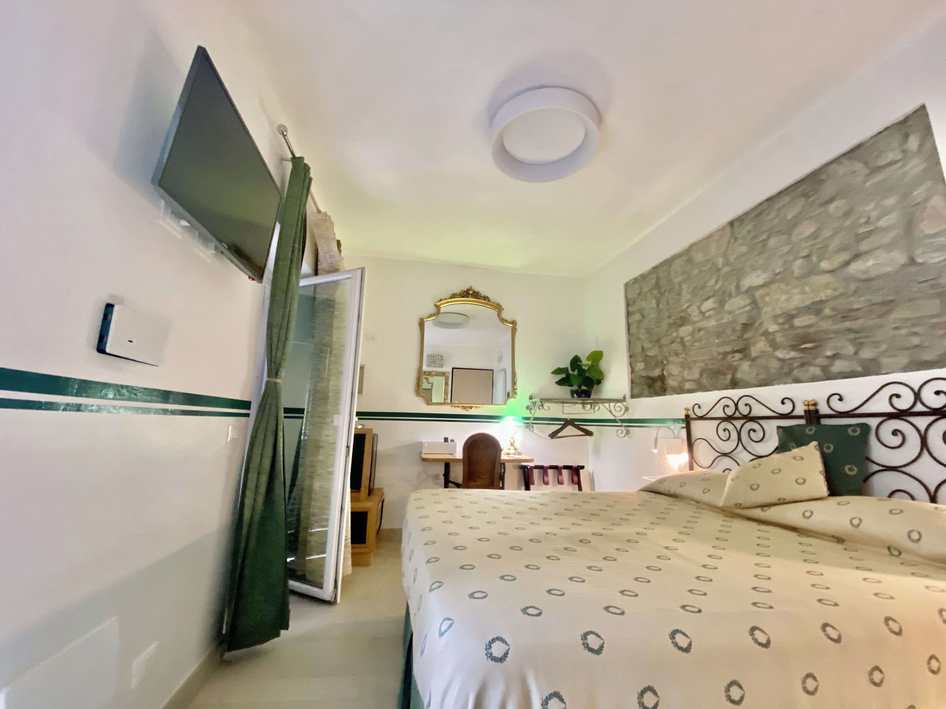 Una camera da letto con un letto, una scrivania, uno specchio e una televisione.
