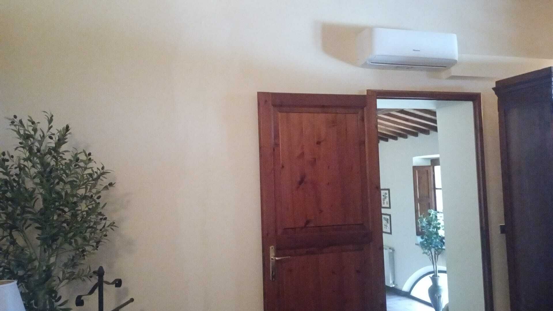 An open wooden door leading to a hallway with a ceiling-mounted air conditioner.