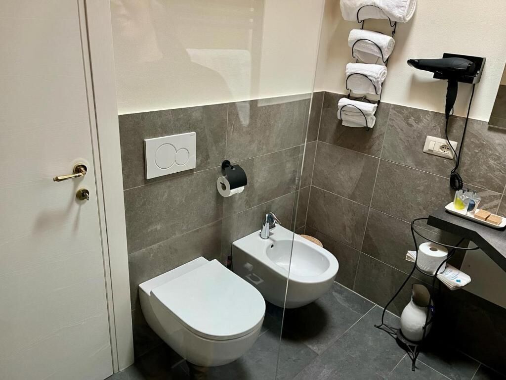 A modern bathroom with a bidet, a toilet, and a towel rack.
