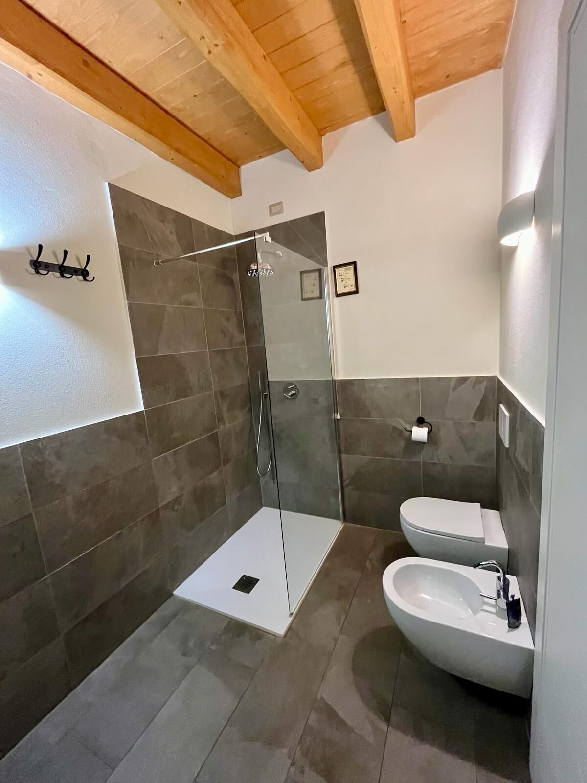 Ein modernes Badezimmer mit einer gläsernen Dusche, einem weißen Waschbecken und einer Toilette.