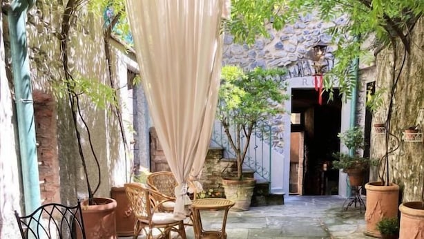 A stone-floored courtyard with wicker furniture and potted plants. - La Corte del Governo 565 (Lezzeno)