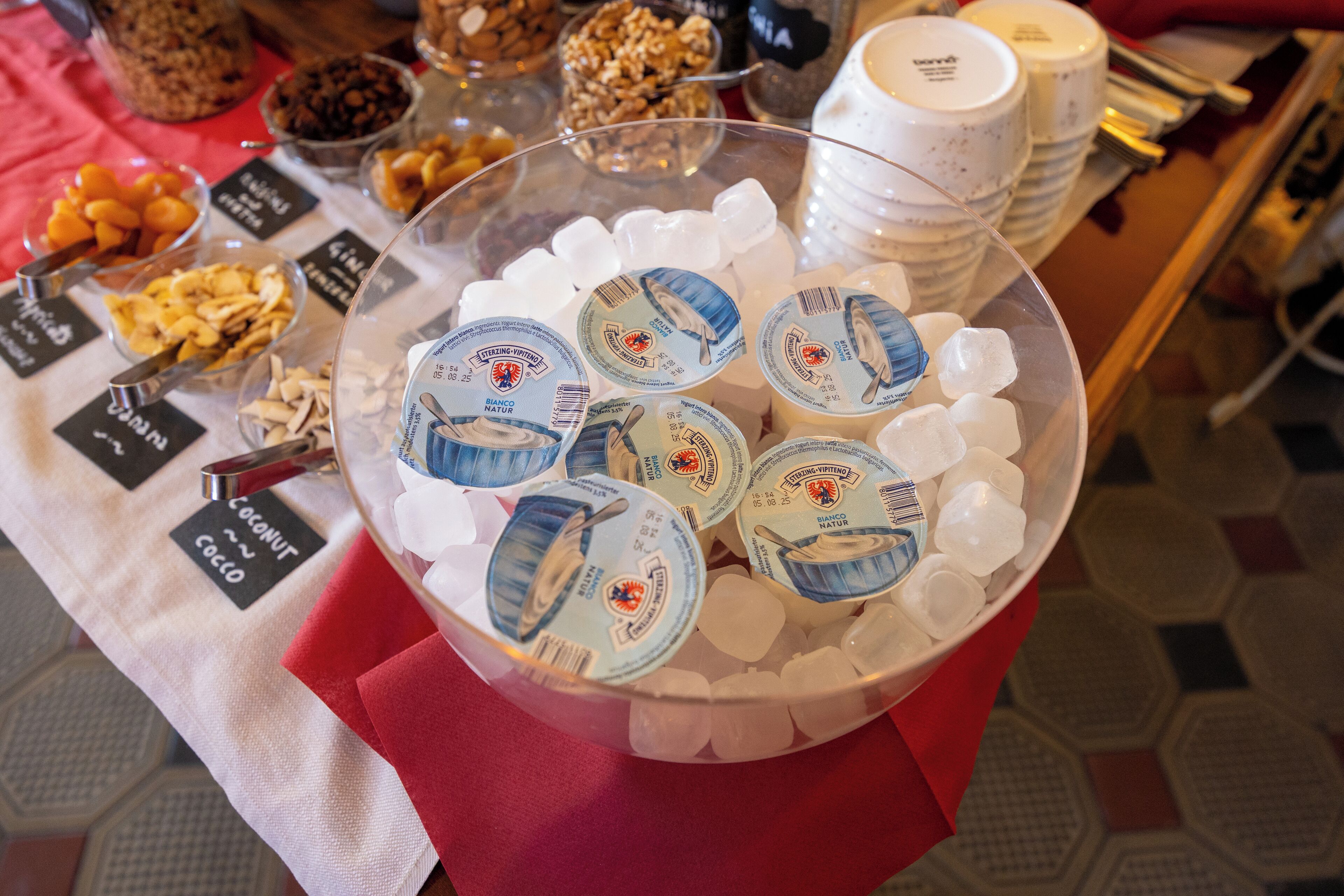 A buffet table with various food items and a bowl of ice cubes.