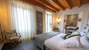 A bedroom with a bed, a chair, a stone wall, and a fireplace. - La Corte del Governo 565 (Lezzeno)